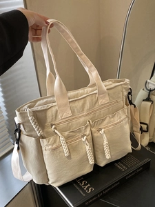 Minimalist beige multi-pocket tote bag with adjustable shoulder strap and woven zipper pulls