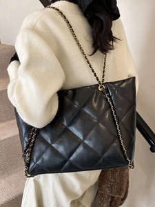 Chic black quilted tote bag with chain strap shown on a model for daily commute style