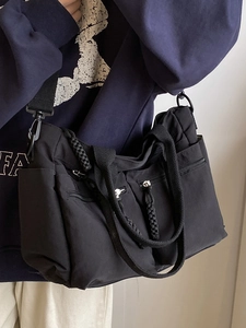 Minimalist black nylon tote bag with multiple zip pockets and adjustable woven shoulder strap