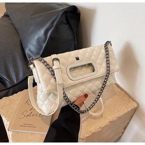 Detailaufnahme einer beigen Stepptasche mit silberner Metallkette und M-Logo