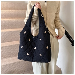 Detail shot of black quilted tote bag with cute beige bear embroidery on nylon fabric