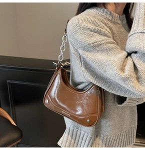 Détail du sac en cuir PU marron caramel brillant avec chaîne argentée sur modèle