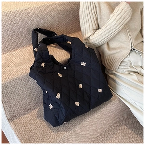 Detail of black quilted tote bag with cute bear embroidery and diamond pattern texture