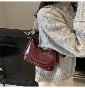Vue détaillée du sac croissant rouge foncé avec chaîne argentée et rivets métalliques