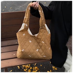 Close-up of caramel quilted tote bag with bear embroidery and metallic snap button