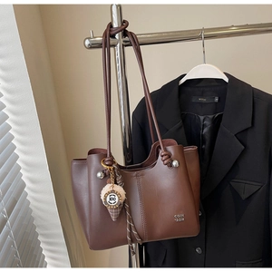 Detail of dark brown leather tote bag with unique twin slim straps and plush charm