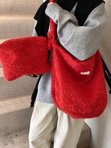 Large red plush wool tote bag and matching pouch set worn by a model in casual wear