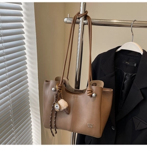 Detail of vintage brown tote bag with ice cream charm and smooth leather texture