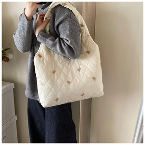 Detail view of large quilted tote bag in off-white fabric with cute brown bear embroidery