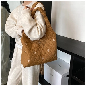Close-up of brown quilted tote bag featuring a cute white bear embroidery detail