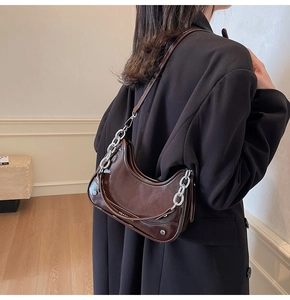 Détail du sac hobo en cuir verni marron foncé avec chaîne argentée et fini vintage