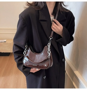 Détail d'un sac à bandoulière en cuir verni marron brillant avec grosse chaîne argentée