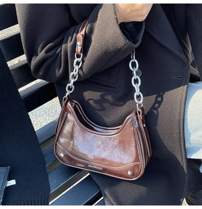 Détail du sac porté épaule demi-lune marron foncé avec fini brillant et chaîne argent