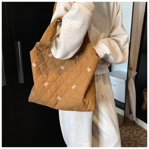 Detailed close-up of brown quilted tote bag with white bear embroidery pattern