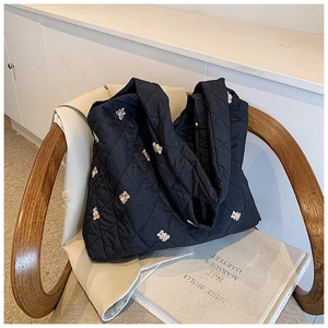 Close-up of quilted black tote bag with cute bear embroidery on a wooden chair