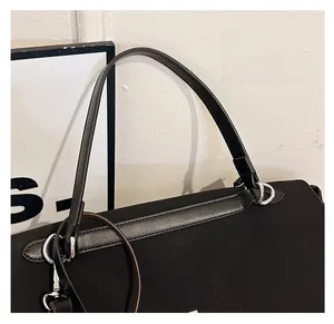 Detail view of black matte leather handbag featuring silver metal ring handle connectors