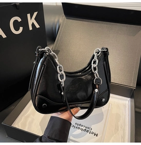 Détail du sac en cuir noir brillant avec chaîne argentée et accents de rivets métalliques