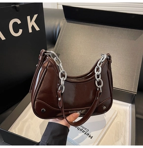 Détail du sac bandoulière en cuir verni marron foncé avec chaîne en métal argenté