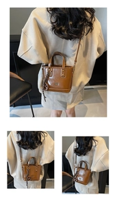 Close-up of brown oiled leather bucket bag with metallic rivets and letter embossing