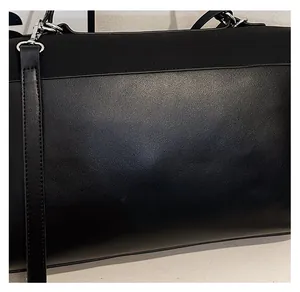 Detailed close-up of premium black leather texture and metal buckle on a shoulder bag