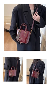 Chic burgundy oil wax leather bucket bag featuring a gold logo and woven knot charm detail