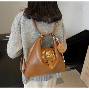 Brown teardrop faux leather bag with gold buckle and plush bear charm on a model