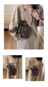 Close-up of brown oiled leather bucket bag with gold hardware and COIH '2DN print