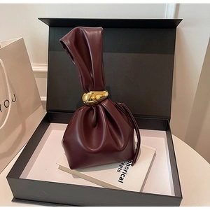 Détail du sac à main rouge vin avec poignée plissée et anneau métallique doré élégant