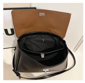 Detail view of the black leather shoulder bag interior with brown lining and metal clasp