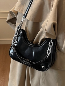 Sac hobo moderne en cuir verni noir avec chaîne argentée porté avec un trench-coat