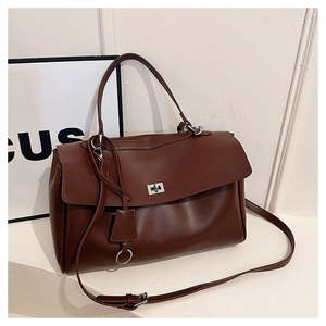 Detailed close-up of dark brown leather handbag with silver lock and adjustable shoulder strap