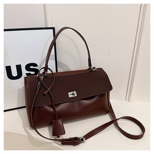 Detail of caramel leather handbag featuring silver twist lock and adjustable strap