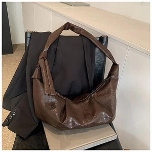 Detailed view of dark brown pleated leather croissant bag with knotted strap