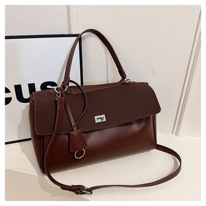 Detail of dark brown leather handbag featuring a metal twist lock and gold-tone hardware