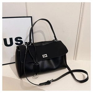 Detail of black leather handbag featuring a silver twist lock and dual texture flap