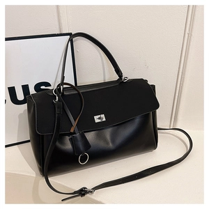 Close-up of black leather handbag featuring a silver metal turn-lock and adjustable strap