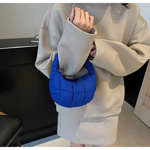 Detail of royal blue quilted crescent handbag with textured square stitching pattern