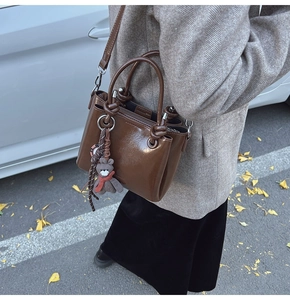 Vue détaillée du sac à main marron en cuir huilé brillant avec pendentif ours et sangle