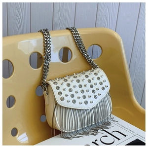 Close-up of white leather handbag with silver rhinestone tassels on a yellow chair