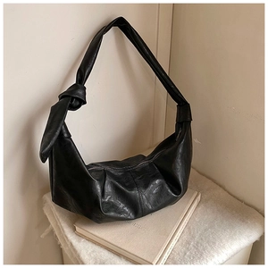 Detail view of the black knotted leather strap and textured surface of the hobo bag