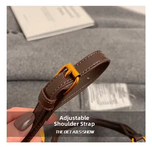 Close-up of adjustable dark brown leather strap with polished gold buckle and stitching