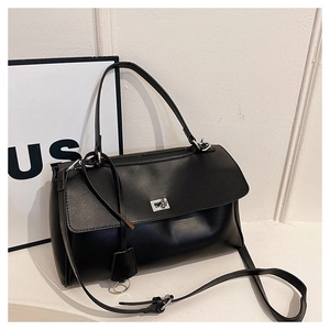 Detail of minimalist black trapezoid handbag showing silver metal turn-lock and matte finish