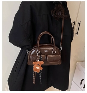 Détail du sac bowling en cuir verni marron avec deux poches et charm ours en peluche