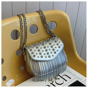 Chic silver crossbody bag with sparkling metal tassels and studded flap on a modern chair