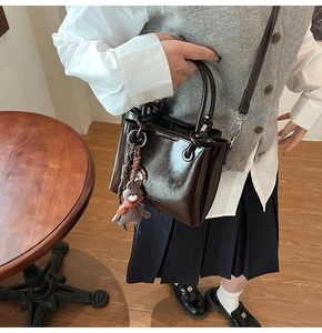 Détail du sac seau en cuir ciré marron foncé avec un joli charme de lapin en peluche