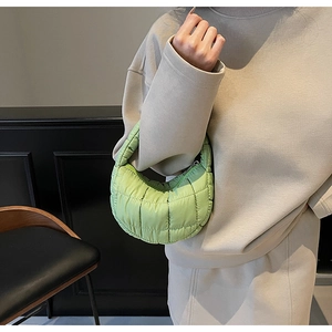 Close-up of light green quilted down bag showing soft padded texture and handle detail
