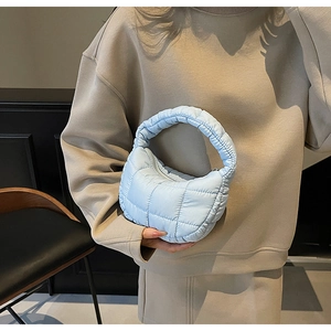 Quilted light blue down handbag for women shown in a modern interior setting