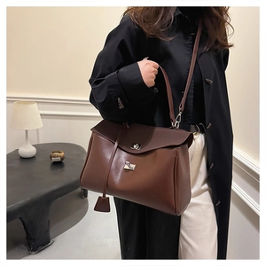 Detailed close-up of dark brown leather handbag with silver metallic dual twist-locks