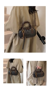 Detail of retro Boston bag showing pebbled leather texture and decorative tassel accessory