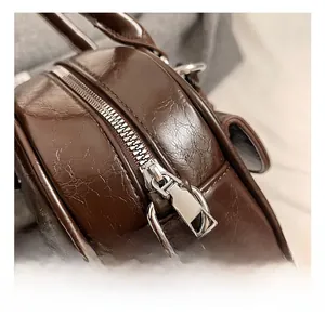 Gros plan sur la fermeture éclair argentée et les détails métalliques du sac bowling brun